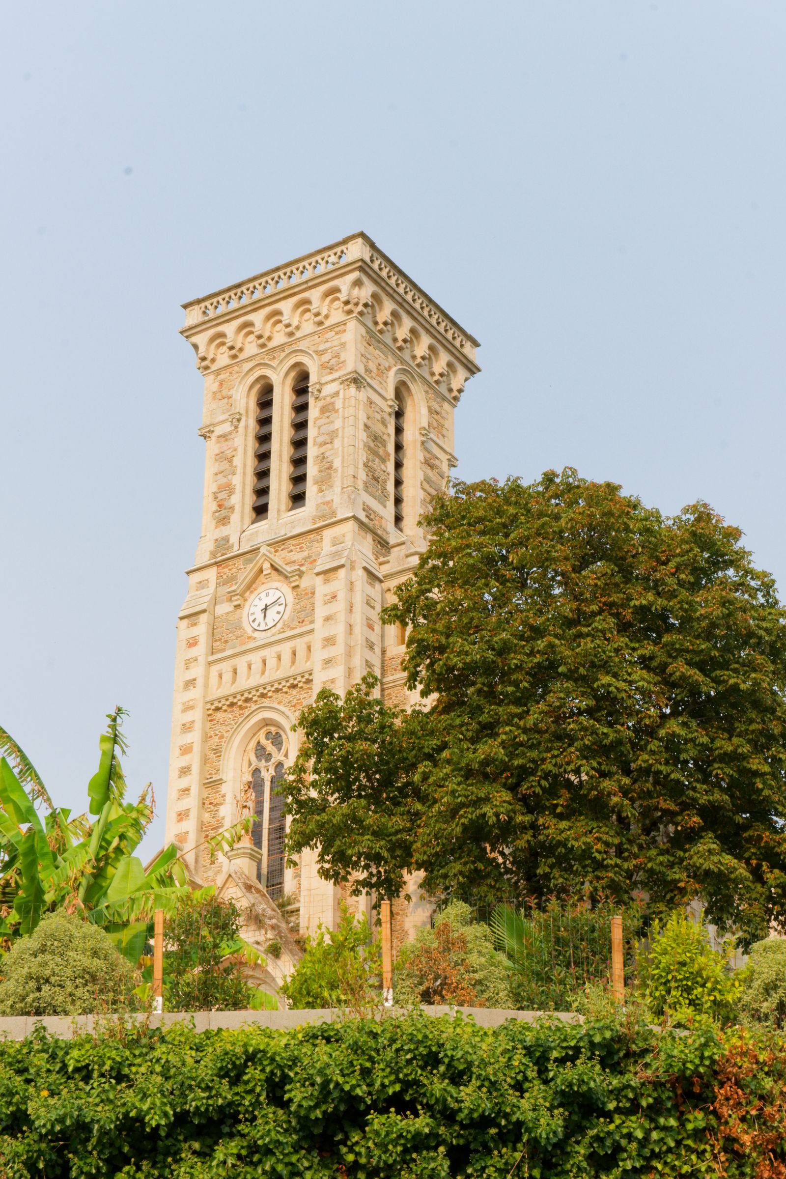 Stone clock tower surrounded by lush greenery in Mayenne, France