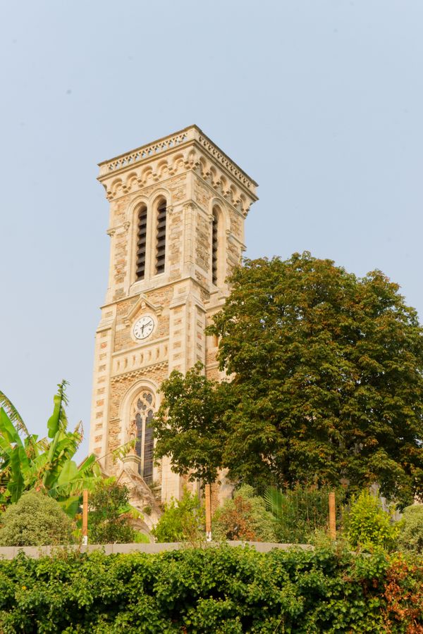 Stone clock tower surrounded by lush greenery in Mayenne, France