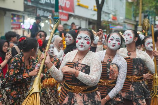 Colorful costumes and face paint in a Yogyakarta street parade celebrating local culture.