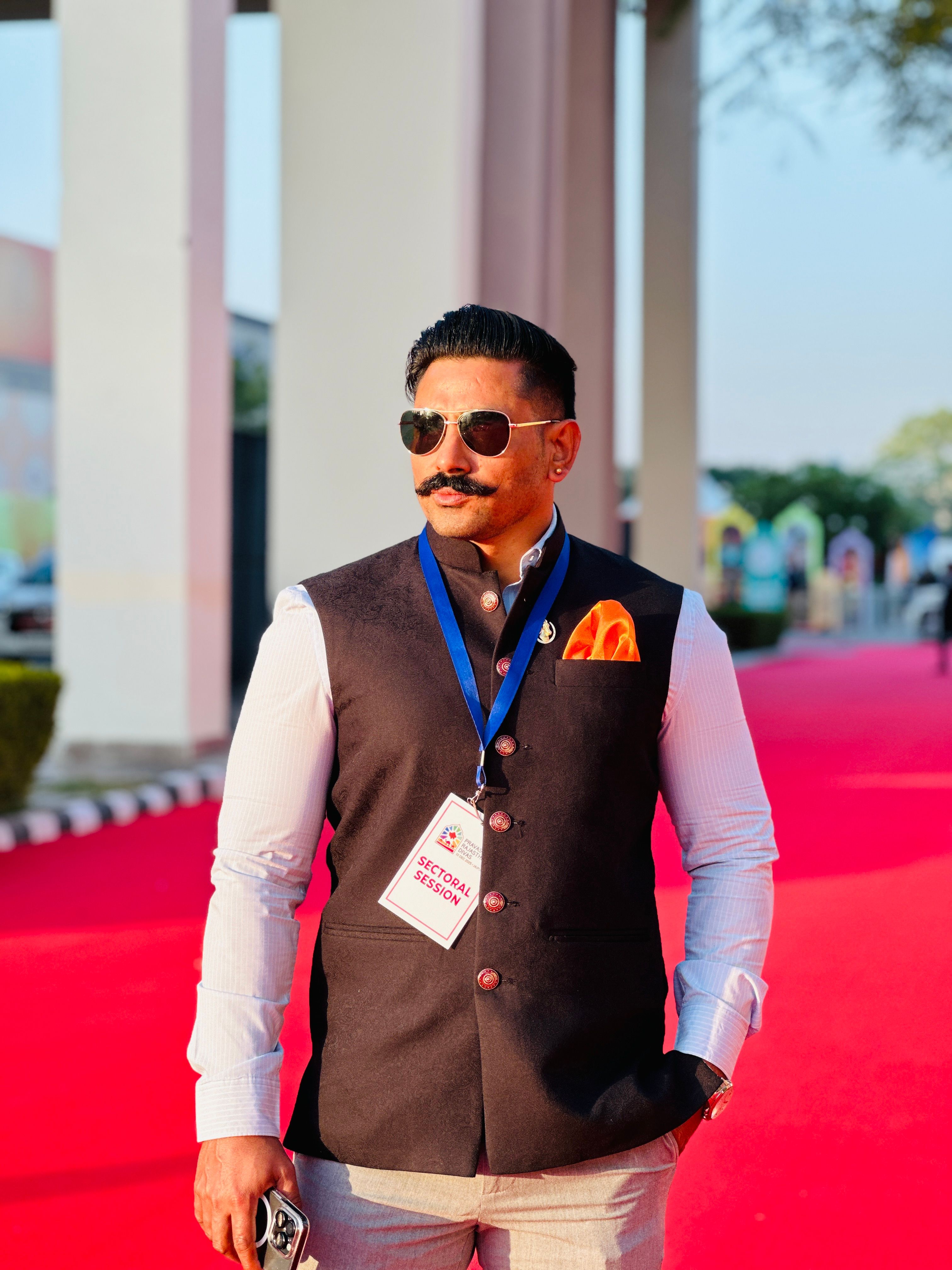 Stylish adult male with sunglasses on a red carpet, exuding confidence and style.