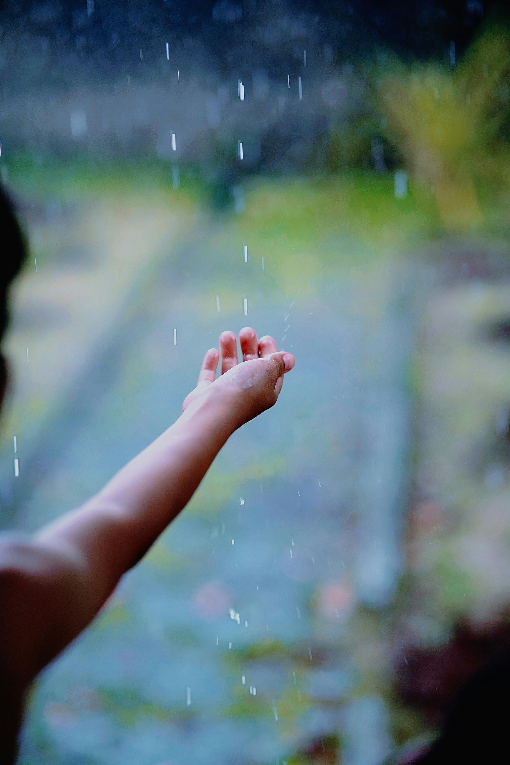 A child's hand reaching out to feel the rain, captured in West Java, Indonesia.