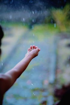 A child's hand reaching out to feel the rain, captured in West Java, Indonesia.
