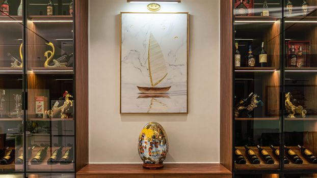 Stylish indoor wine cabinet with an elegant painting and decorative vase in Hải Phòng, Việt Nam.