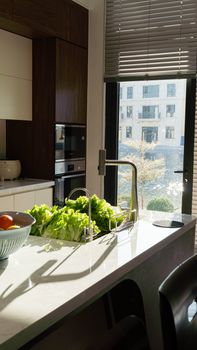 Sunlit modern kitchen interior with fresh vegetables on counter, showcasing urban lifestyle and design.