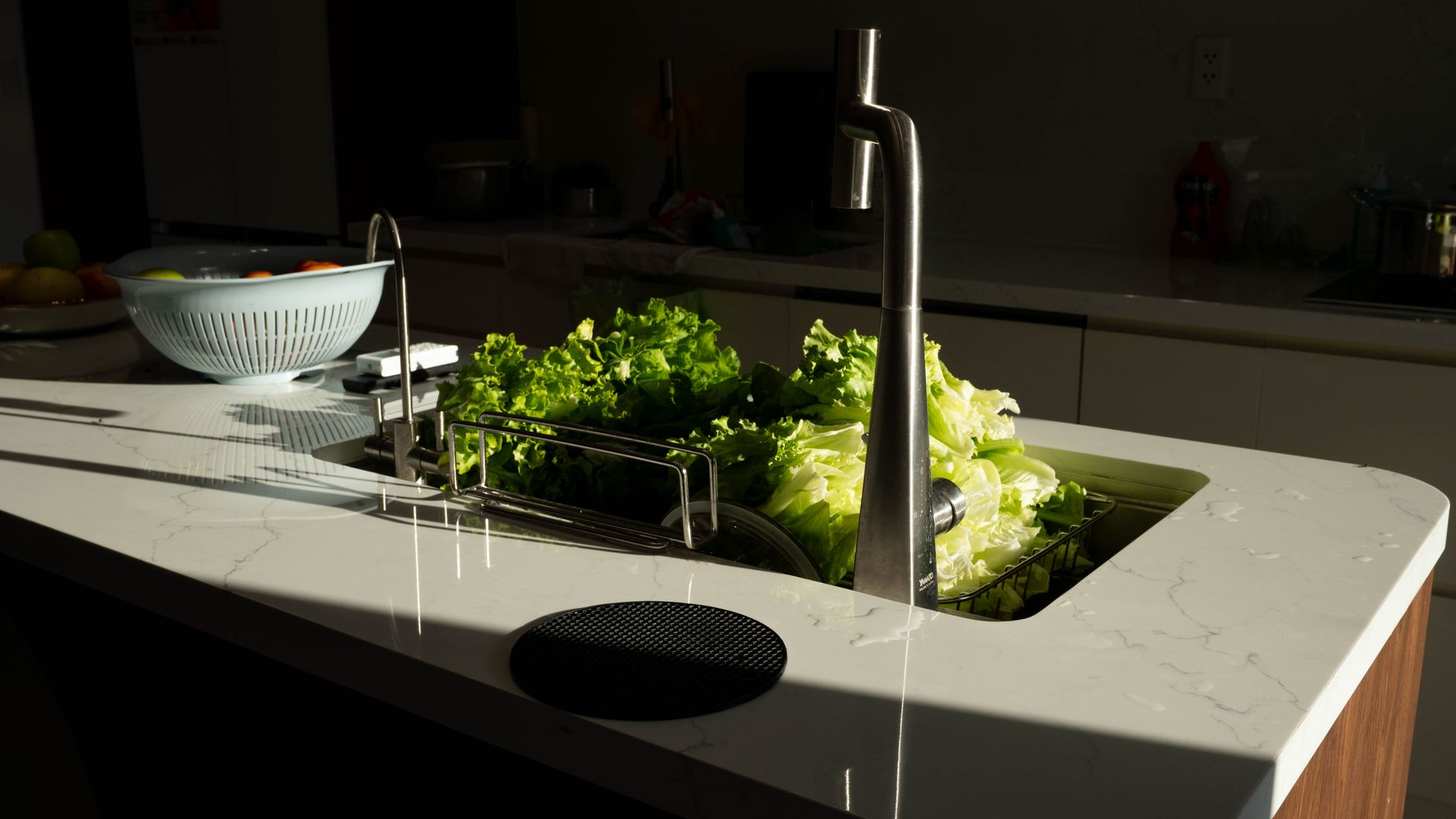 Green lettuce being washed in a modern kitchen sink under sunlight in Hải Phòng, Việt Nam.