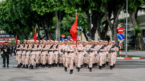 Free Vietnamese soldiers in a parade march down a tree-lined street in Hanoi. Stock Photo