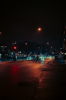 Urban night scene with neon reflections and a cyclist crossing, creating a cinematic atmosphere.