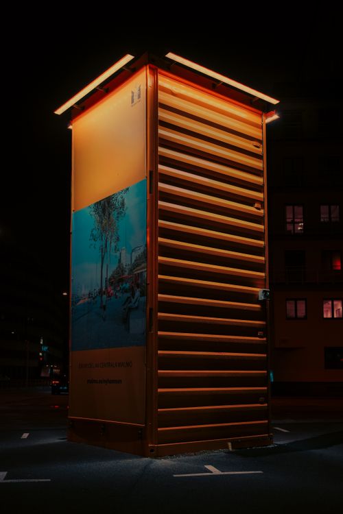 Free A glowing orange urban structure with neon lights in a dark cityscape at night. Stock Photo