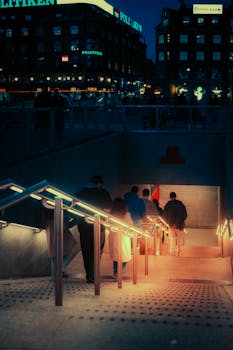 Moody street photo of people entering a Copenhagen metro station at night.