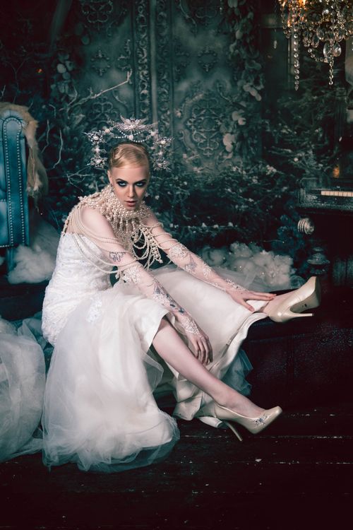 Free A bride in a sophisticated white dress seated in a gothic setting with chandeliers. Stock Photo
