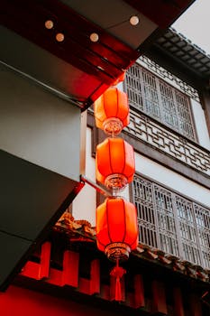 Red lanterns glow under traditional Chinese architecture in Nanjing, China, at twilight.
