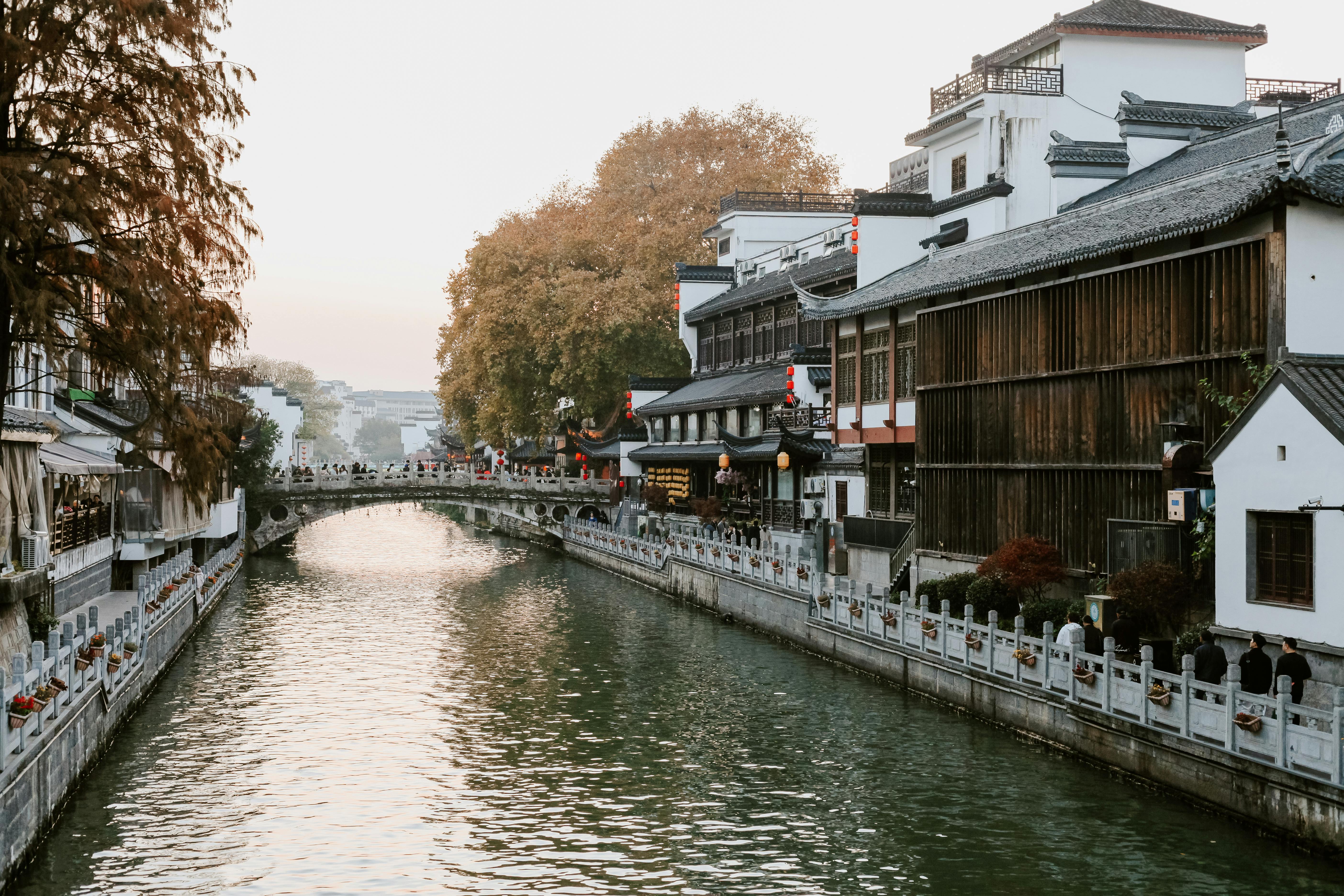 Tranquil scene of a canal lined with traditional Chinese architecture in Nanjing during fall.