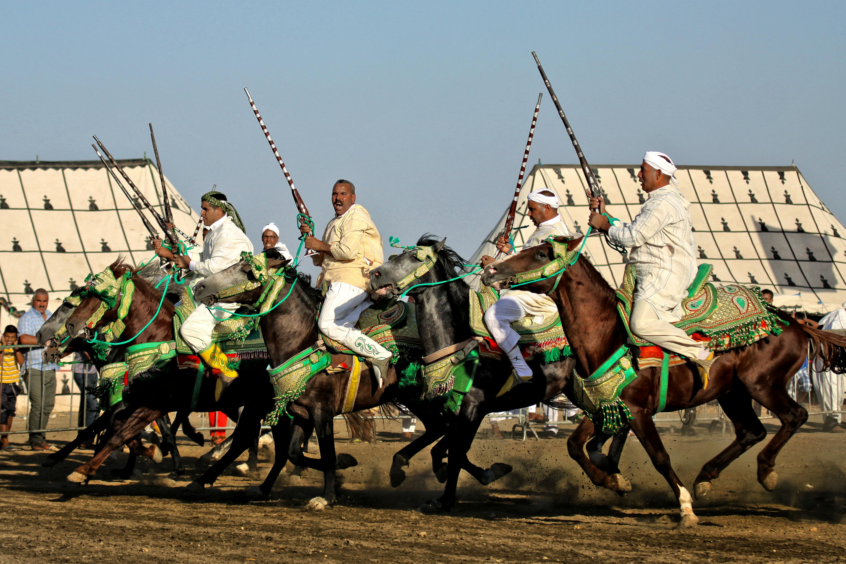 Horsemen in traditional attire participate in an exciting cultural festival race, showcasing skills and heritage.