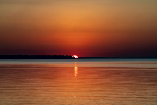 A breathtaking sunset with vibrant colors reflecting on a tranquil water surface.