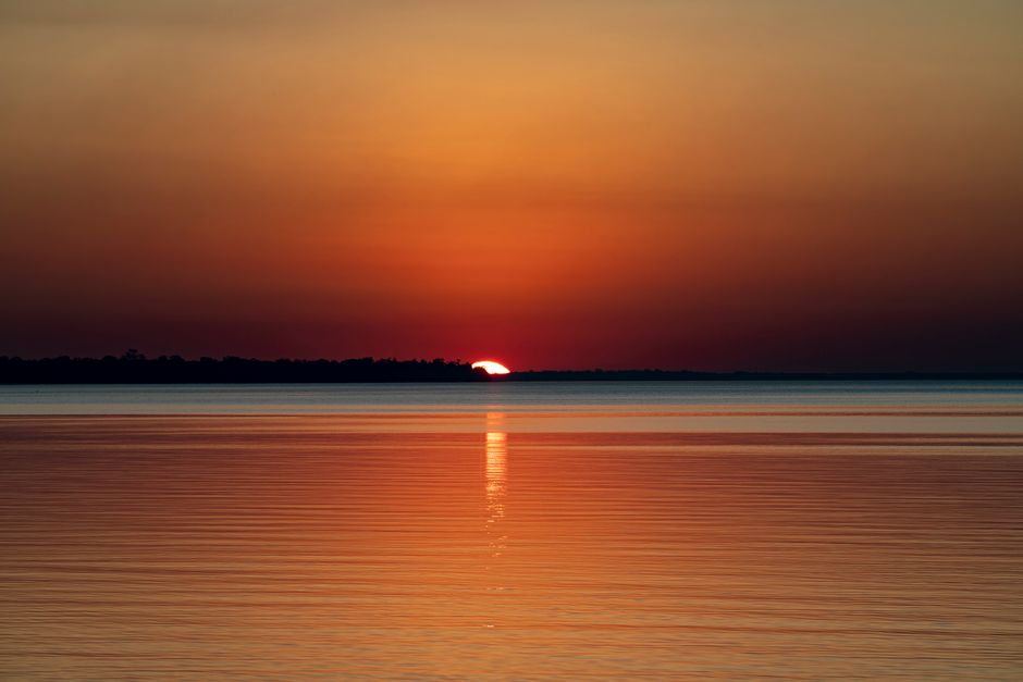 A breathtaking sunset with vibrant colors reflecting on a tranquil water surface.