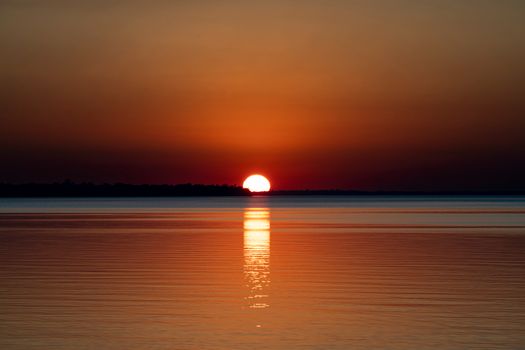 A stunning sunset with vibrant hues reflecting over tranquil ocean waters, creating a peaceful scene.