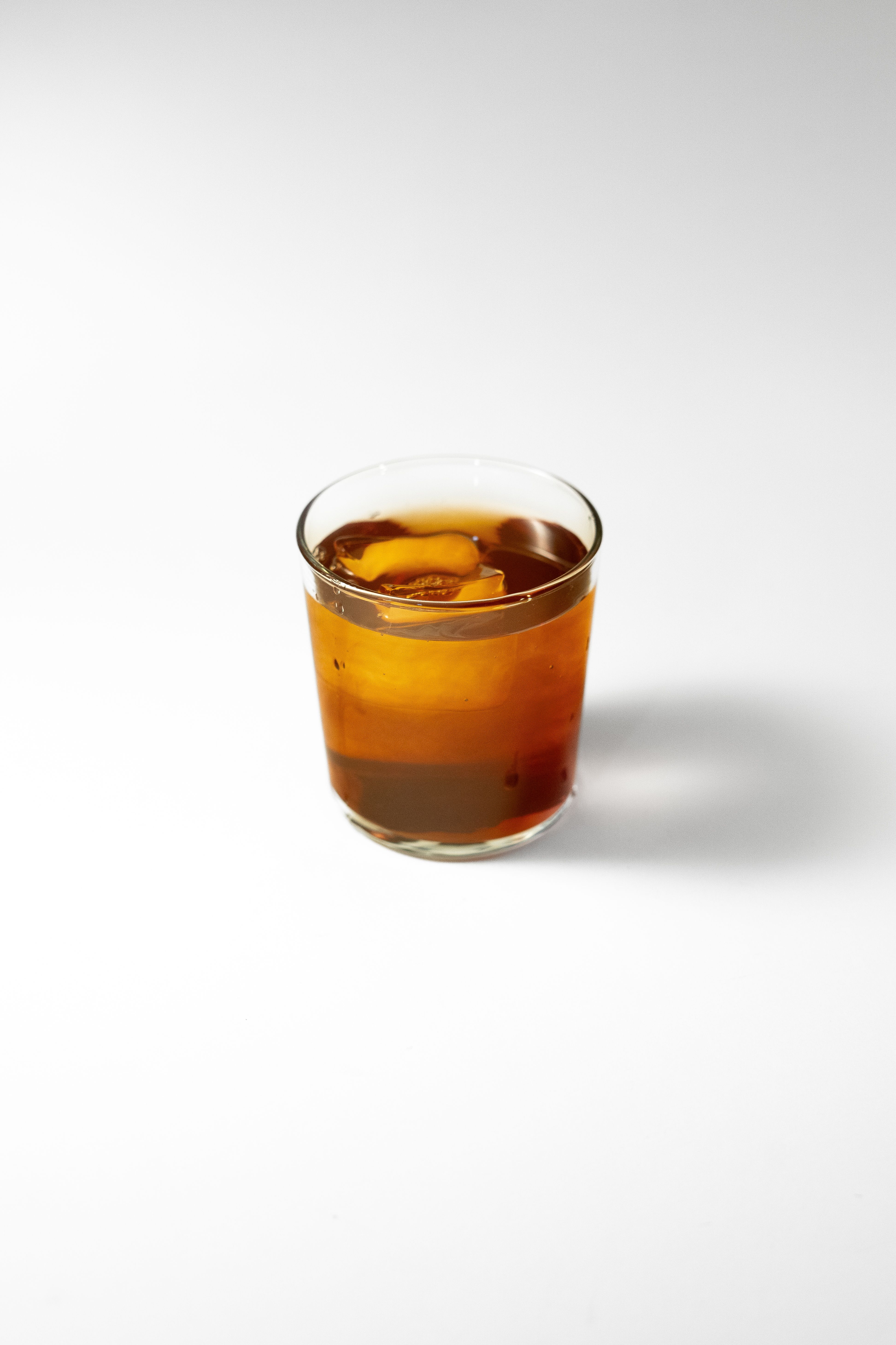 Minimalist shot of iced cold brew coffee in a clear glass, highlighting simplicity and refreshment.