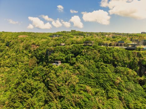 Aerial panorama of lush green cliffs and luxury villas in Bali, Indonesia.