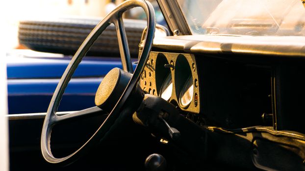 Close-up of a vintage car dashboard and steering wheel in sunlight.