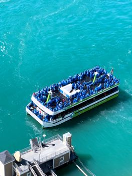 A captivating view of a boat tour with tourists in blue ponchos at Niagara Falls.