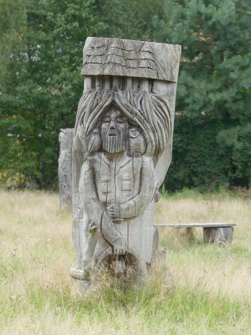Free A carved wooden sculpture depicting a historical figure in a grassy outdoor setting. Stock Photo