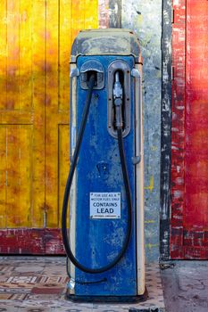 Vintage blue gas pump in front of a vibrant, weathered wall. Classic retro style.