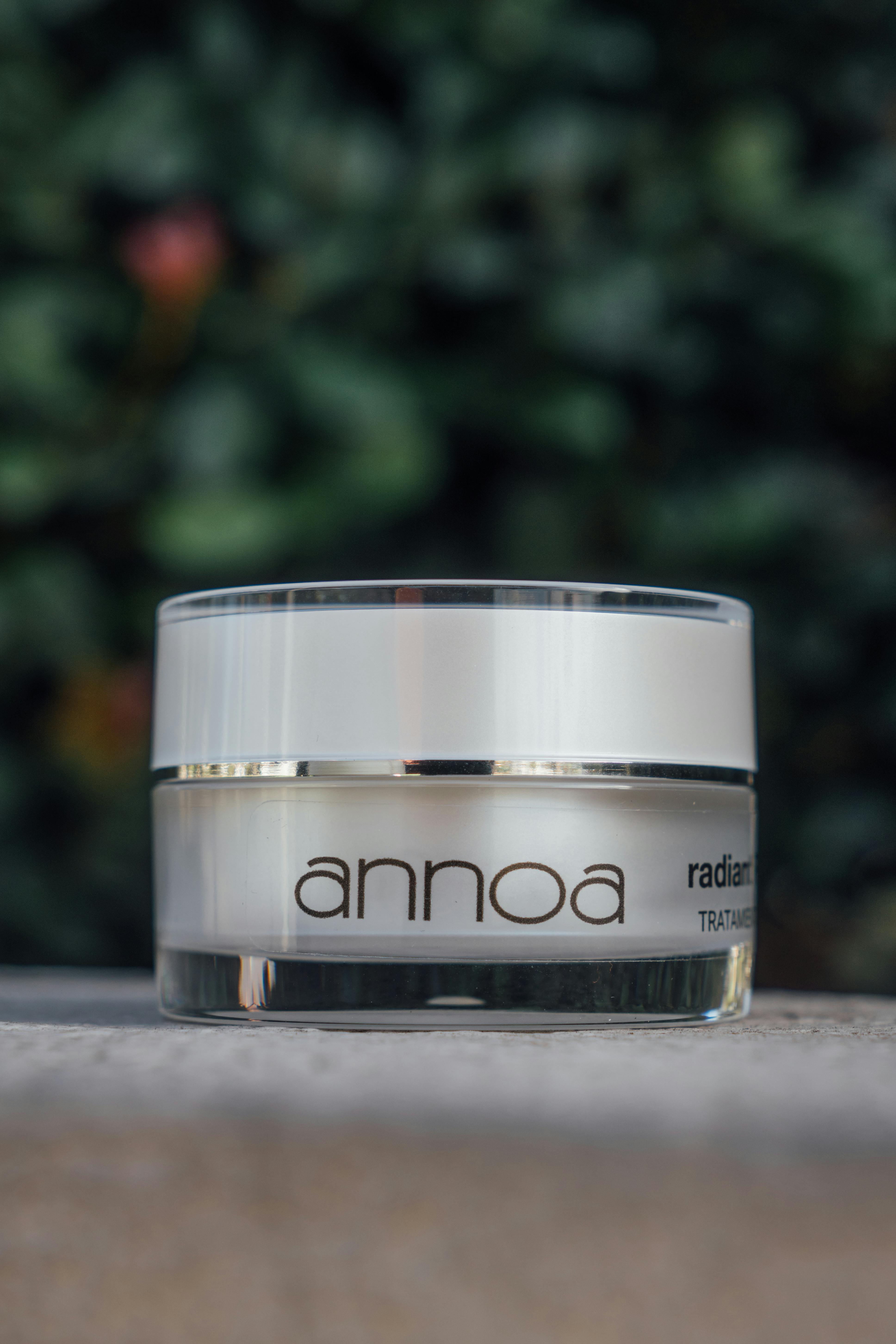 Close-up of a luxurious skincare cream jar outdoors with blurred greenery background.