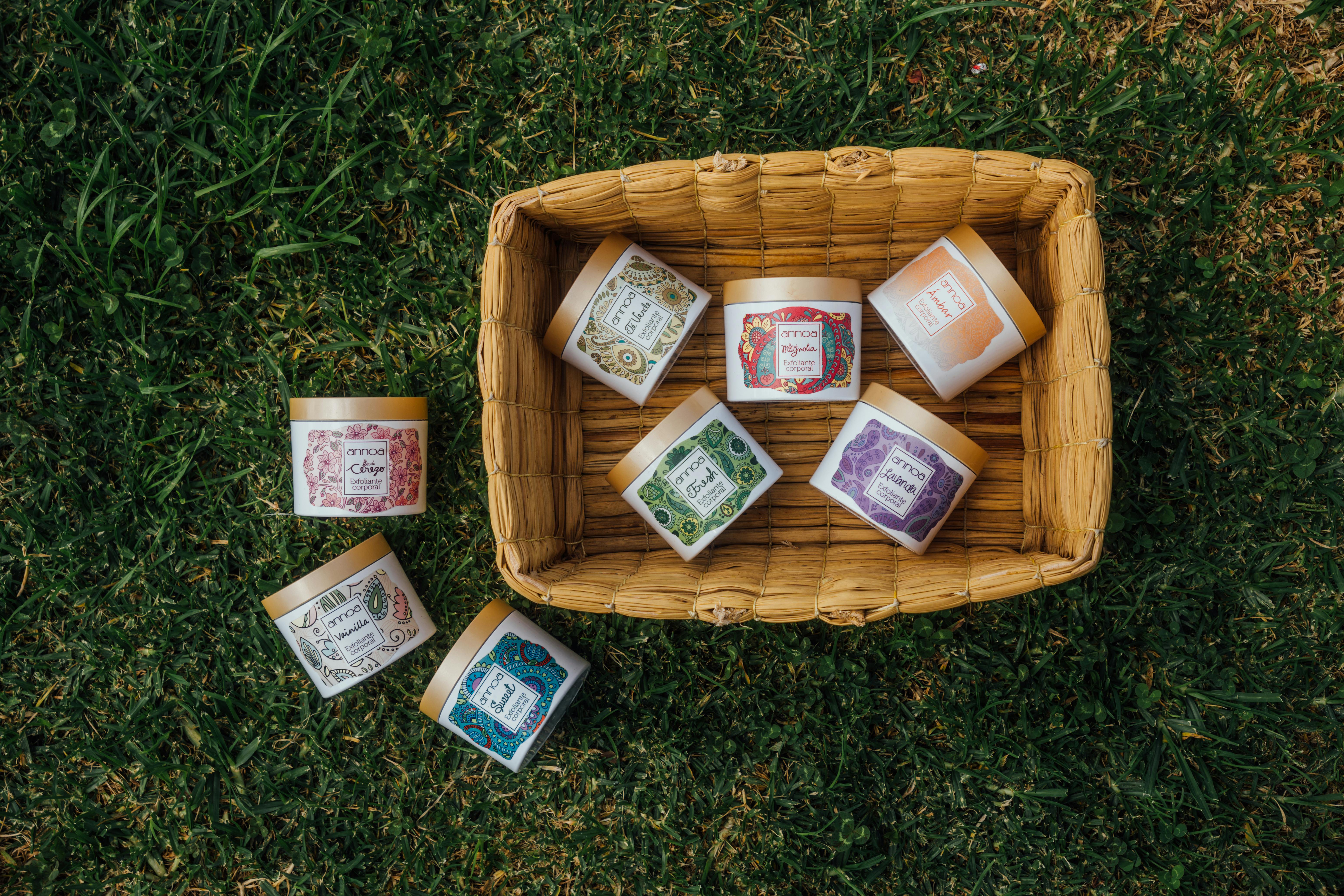 Top view of assorted herbal creams arranged in a wicker basket on grass, showcasing natural skincare products.