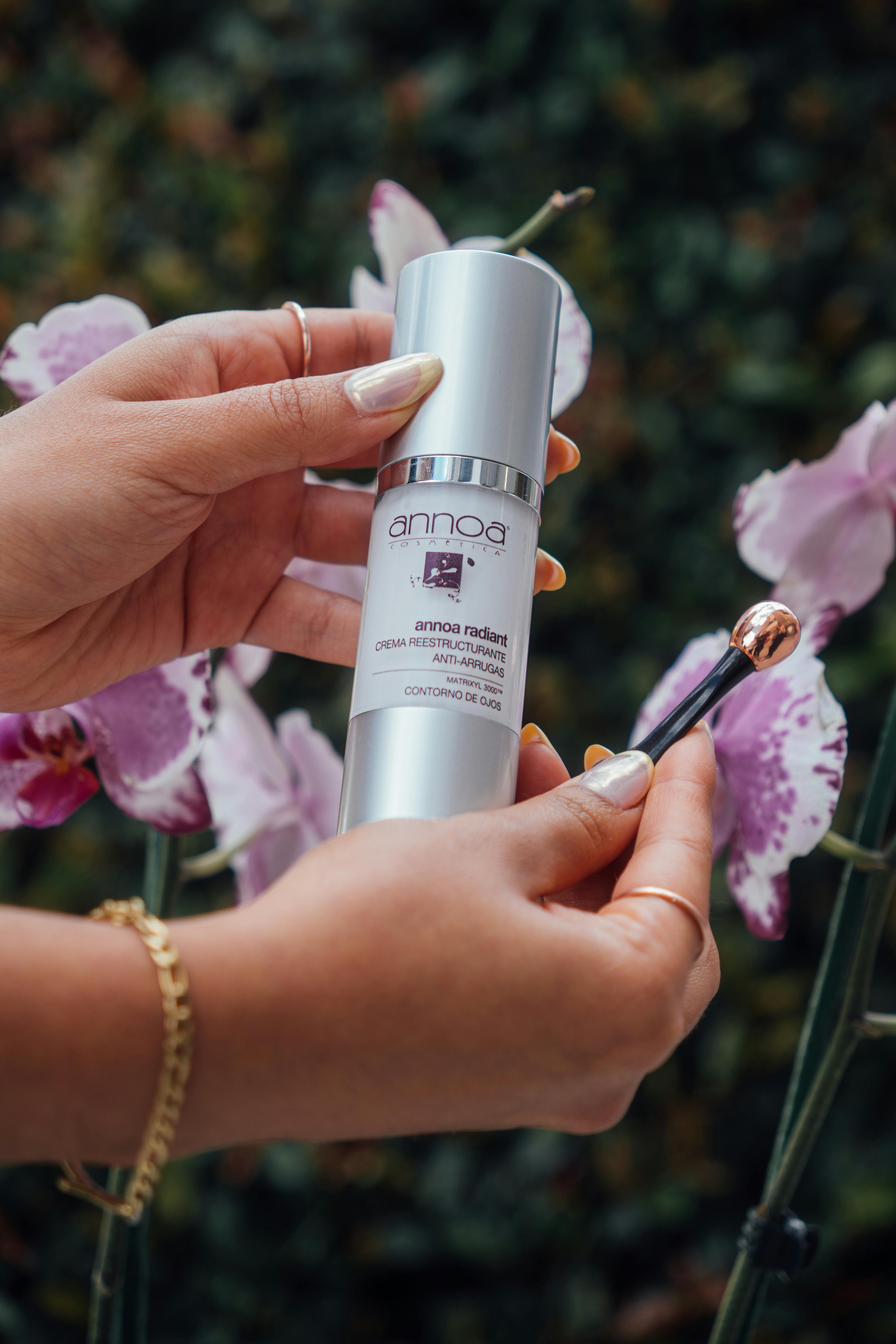 Elegantly held skincare product with orchids, showcasing beauty and care.
