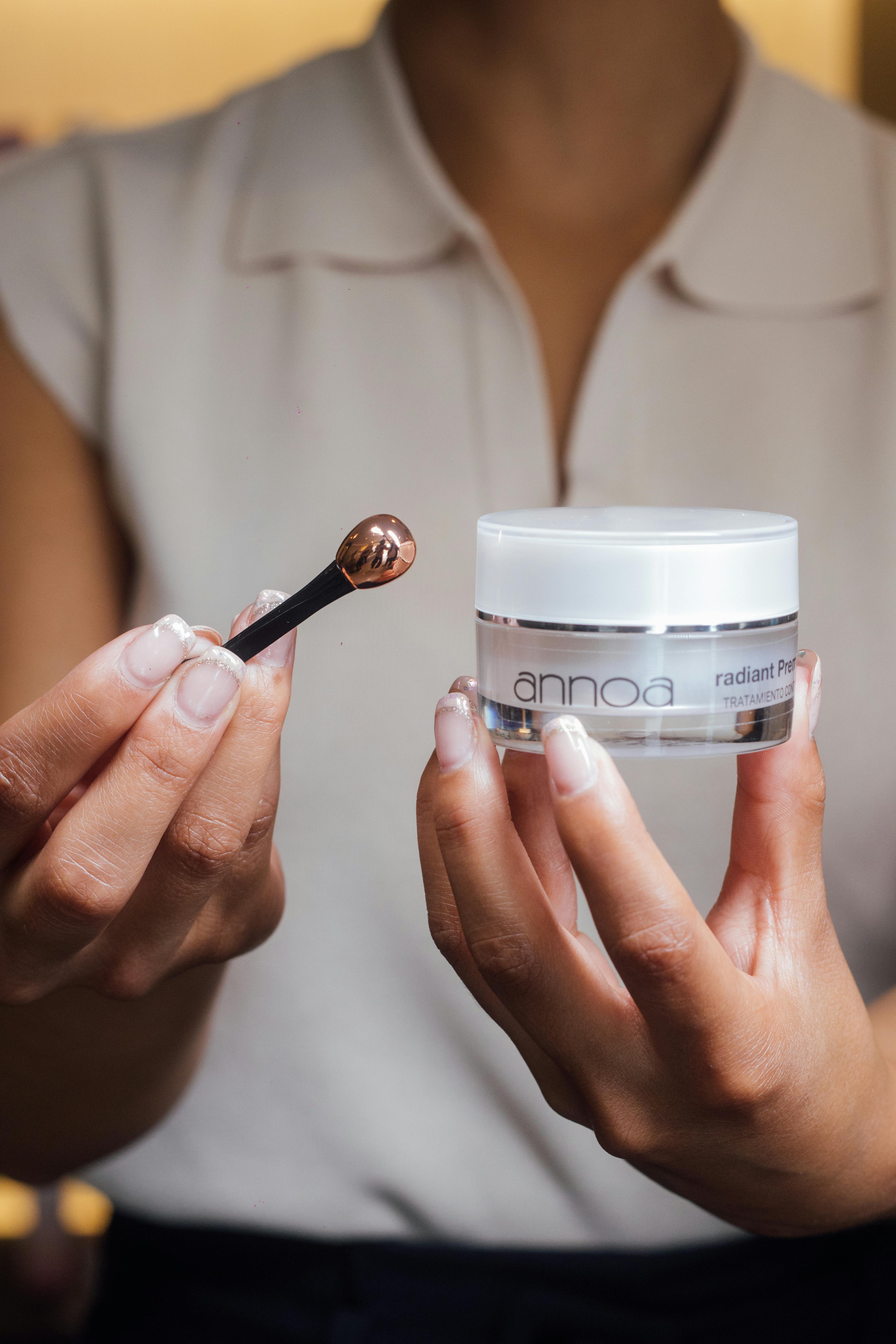 Close-up of a woman applying cream with an applicator, highlighting skincare routine.