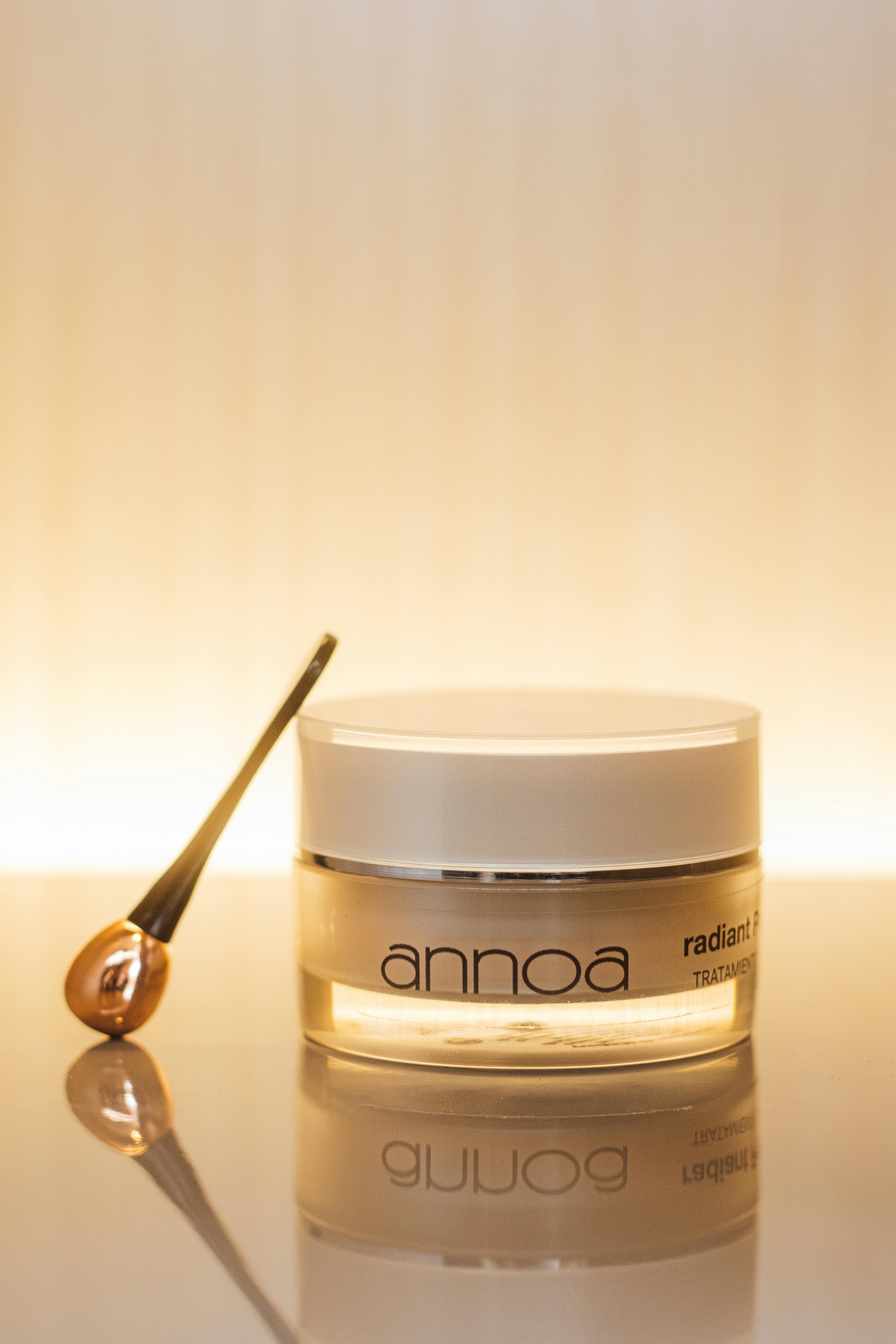 An elegant skincare jar with a spoon under warm, reflected light creating a luxurious and serene atmosphere.