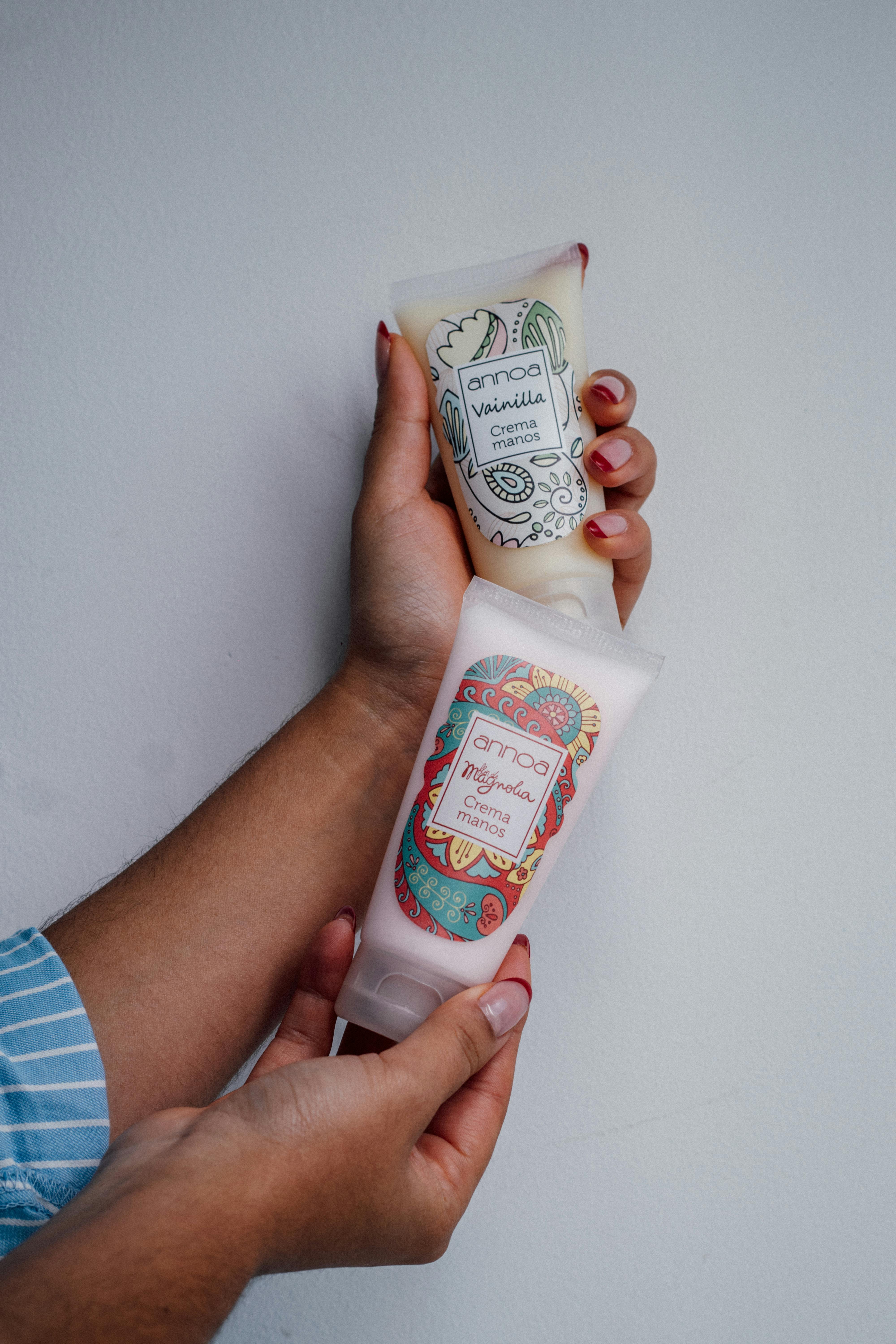 Person holding two aromatherapy cream tubes labeled vanilla and fig against a plain background.