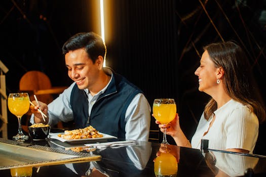 Smiling couple dining with drinks at an elegant restaurant, enjoying a warm and lively ambience.