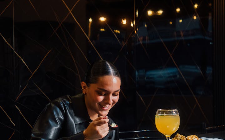 Woman savoring a meal at a chic, dimly-lit restaurant.