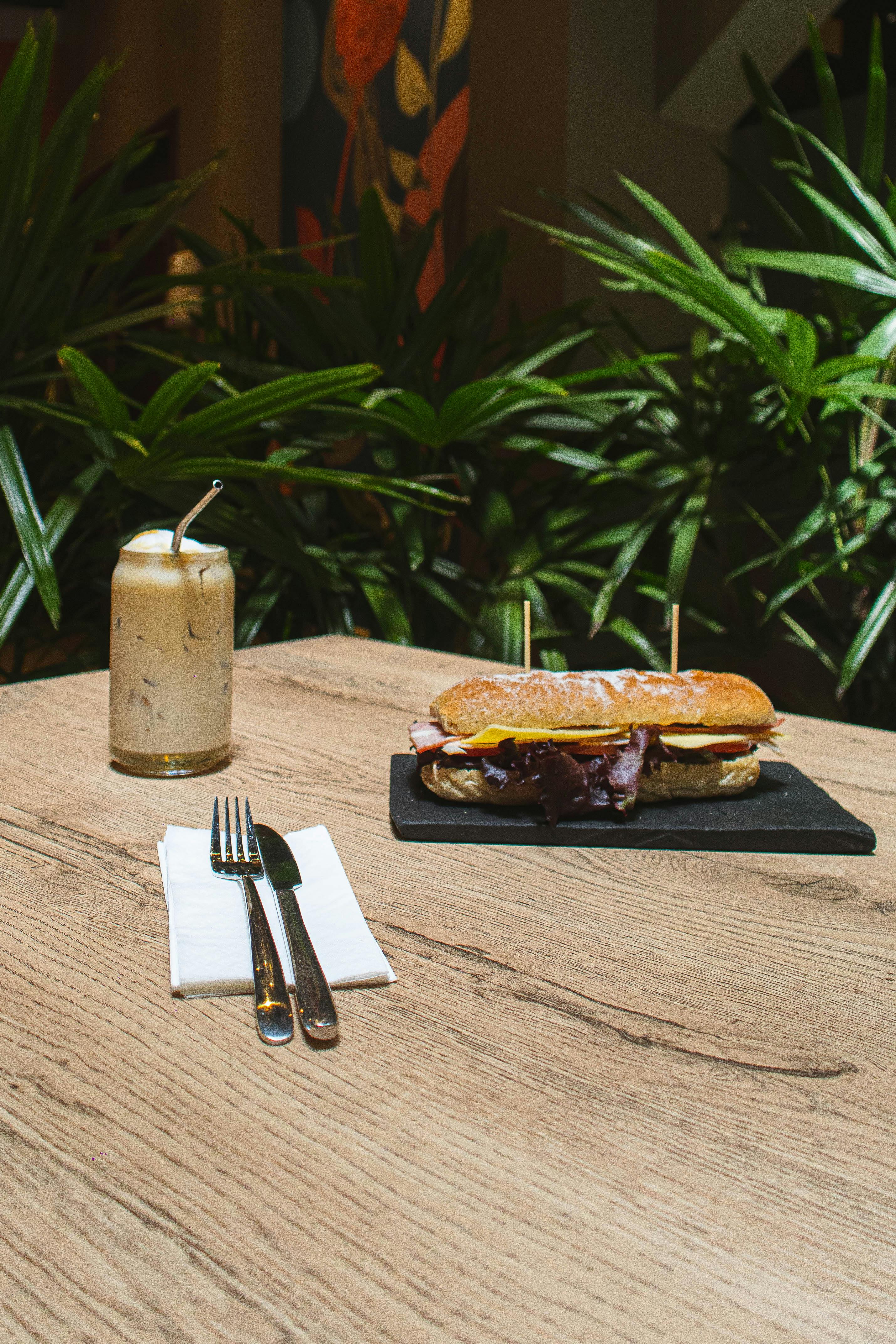 A tasty baguette sandwich paired with iced coffee on a wooden table, perfect for brunch.