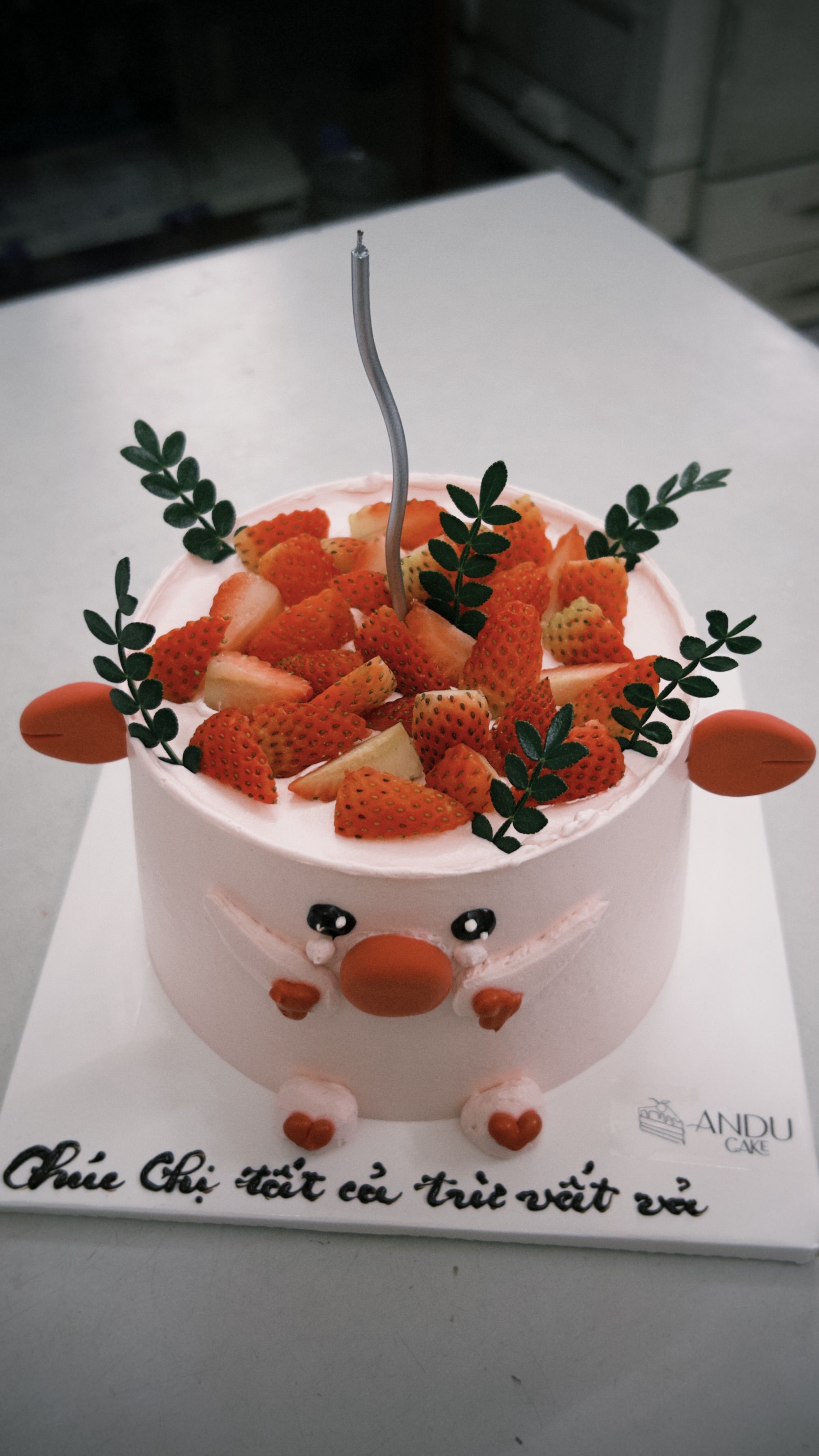 Adorable animal-themed cake topped with fresh strawberries and greenery, perfect for celebrations.