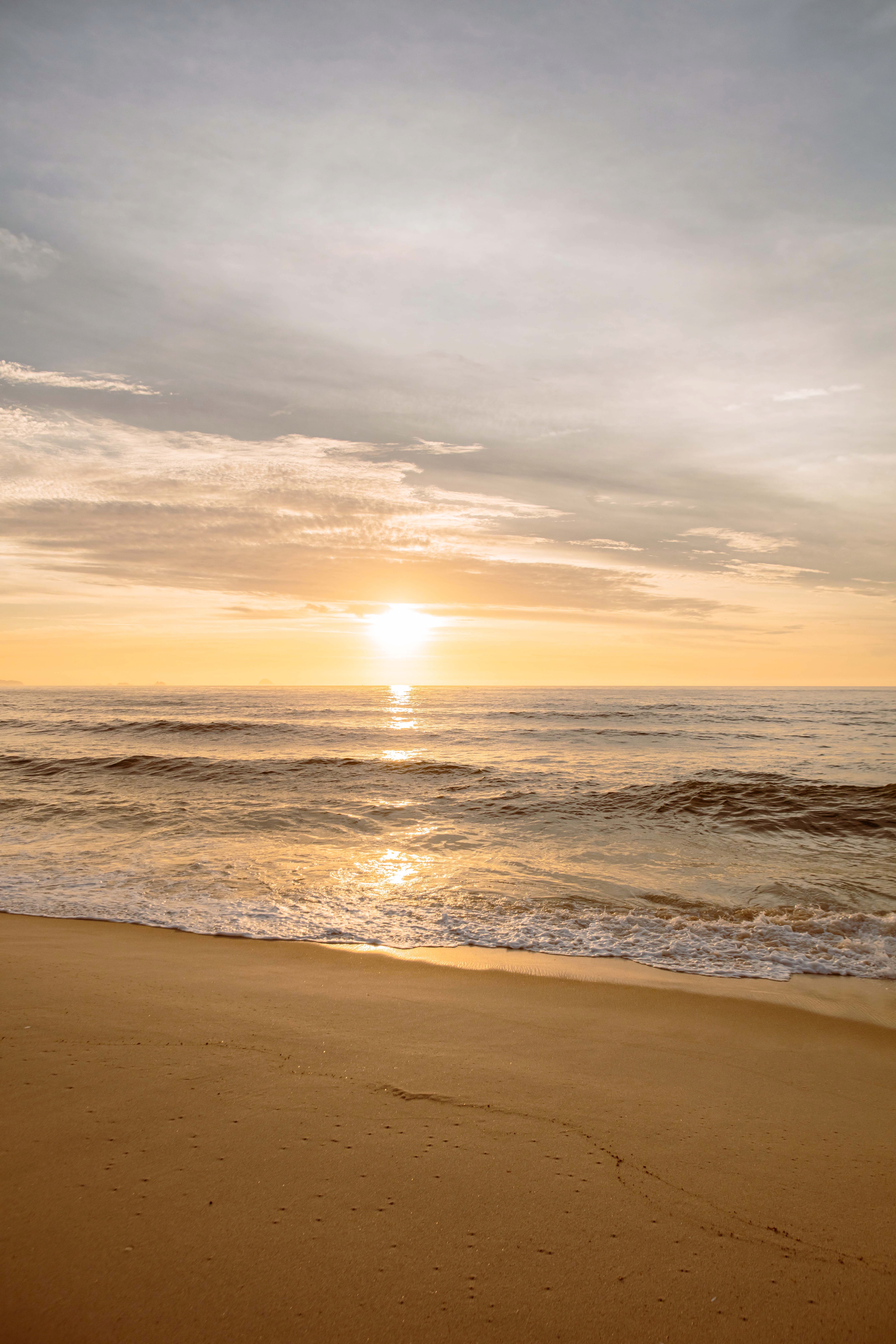 Serene Beach Sunrise Over Calm Ocean Waves · Free Stock Photo