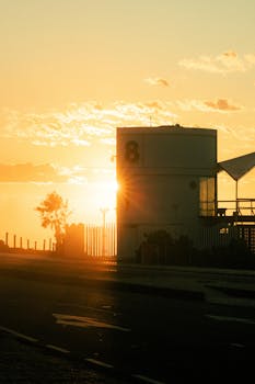 Silhouette of a beachside structure against a vibrant sunset with dramatic clouds.