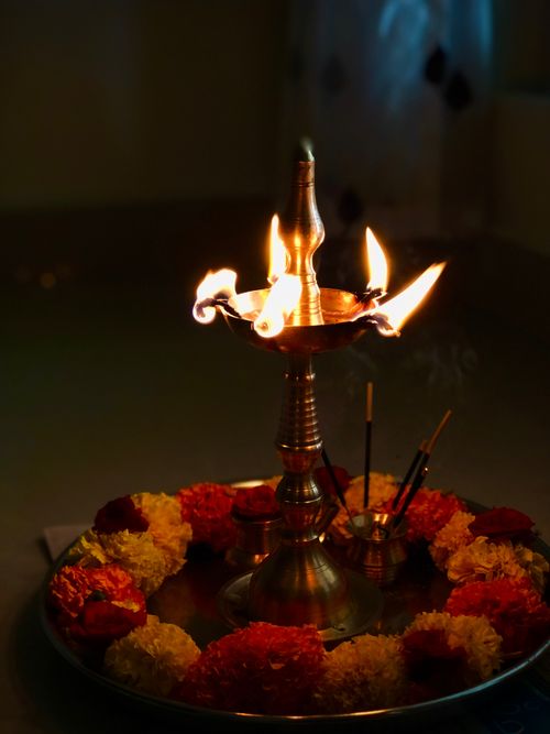 Free A lit brass oil lamp surrounded by marigold flowers, ideal for Diwali celebrations. Stock Photo