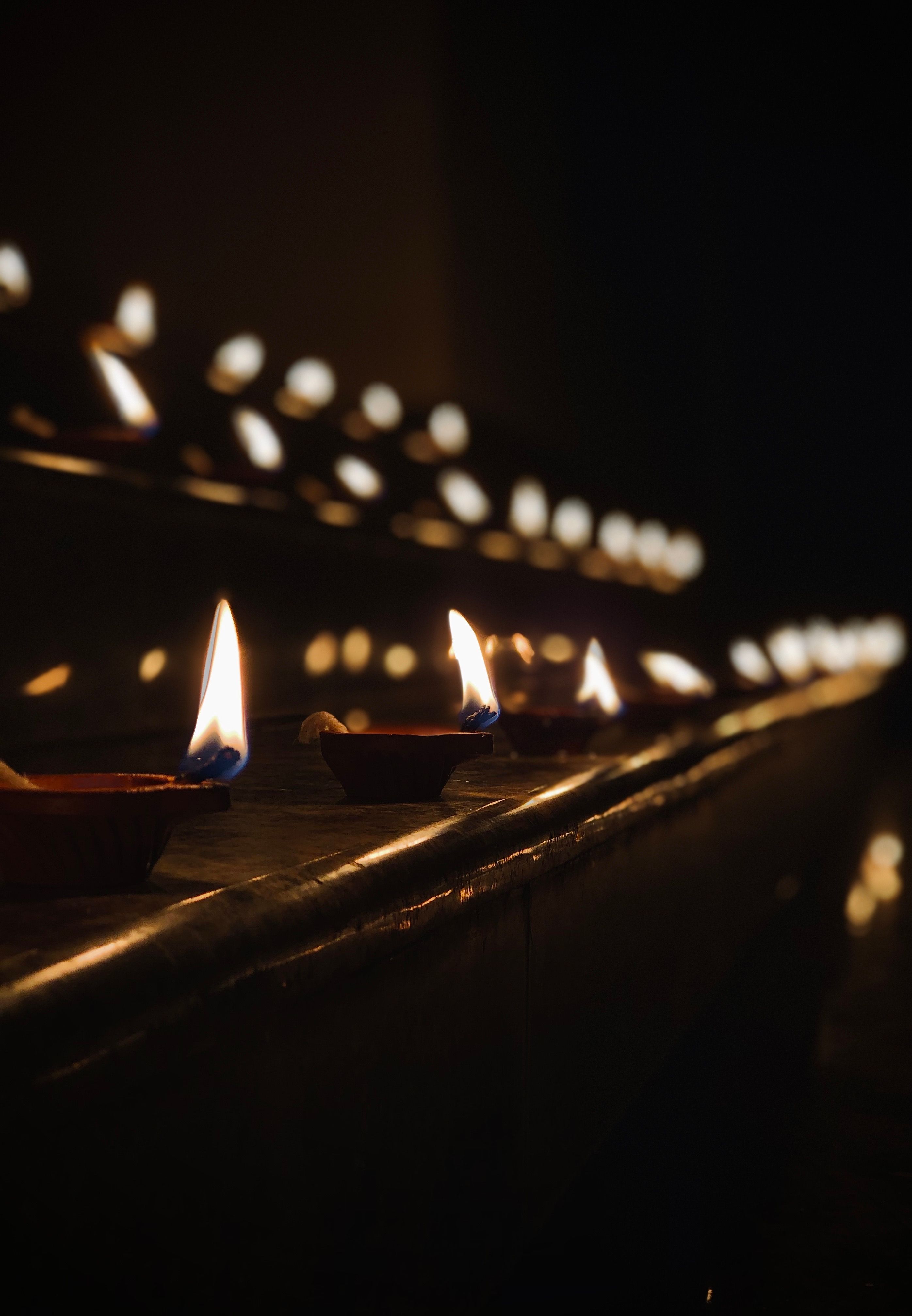 Row of Lit Oil Lamps in Dark Ambiance · Free Stock Photo