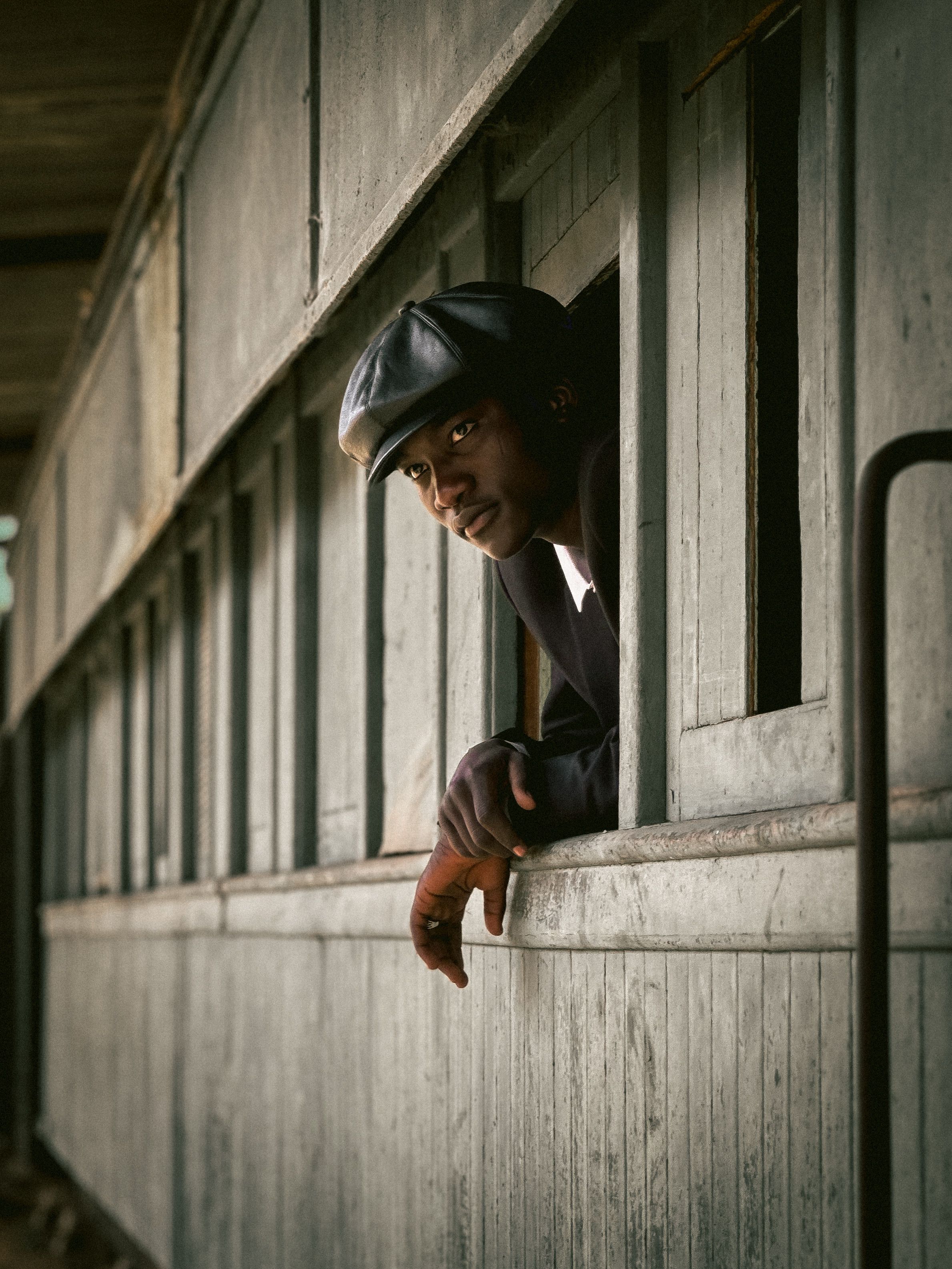 A thoughtful man leans out of a vintage train car window, capturing a moment of contemplation.