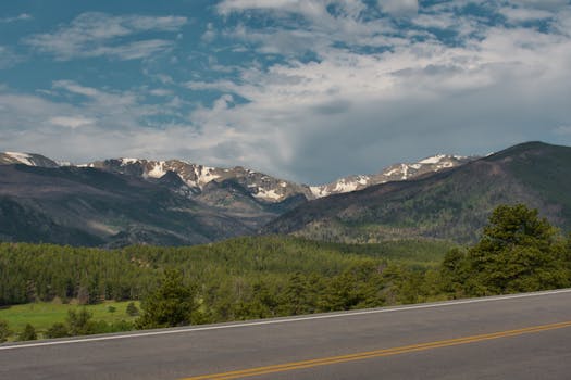 Breathtaking view of snow-capped mountains and green forest in Rocky Mountain National Park.