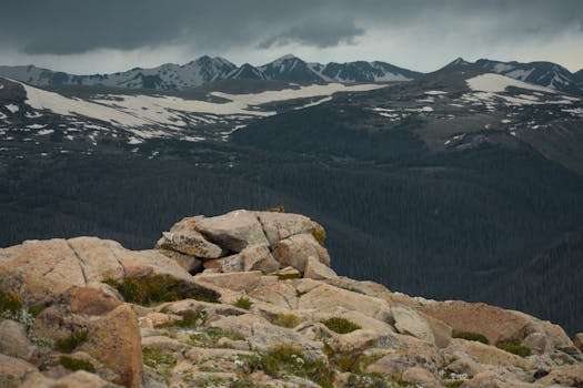 Scenic view of a mountain range with rugged rocks in the foreground under a cloudy sky.