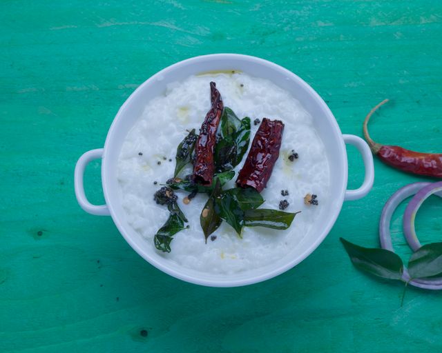 A bowl of traditional South Indian curd rice garnished with spices and herbs.