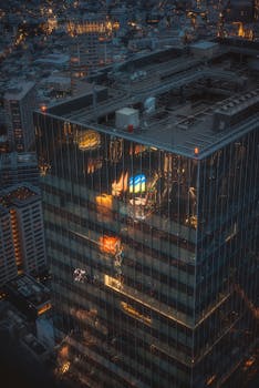 Dramatic aerial shot of a skyscraper in Tokyo at night, reflecting city lights.