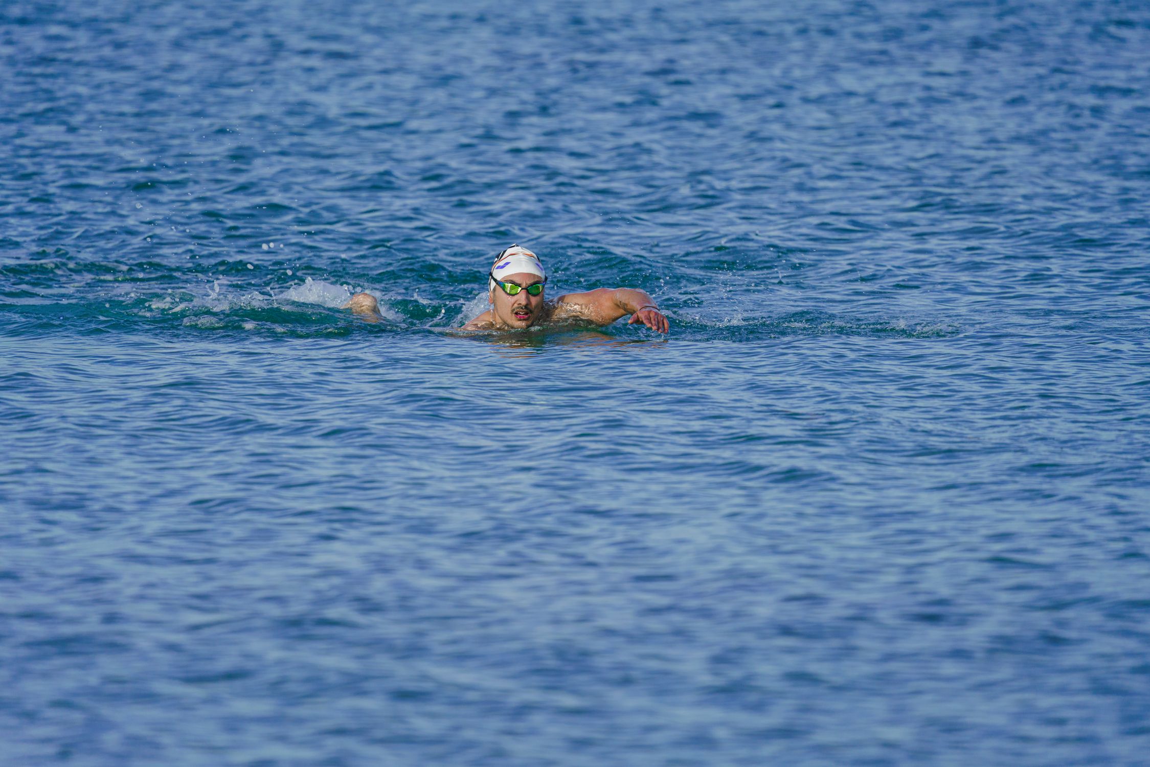 Athlete swimming in open sea near Kuşadası, Türkiye on a sunny day.