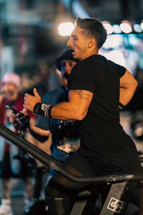 Free Fit man exercises on treadmill during an energetic outdoor fitness event at dusk. Stock Photo