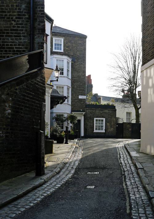 Free Charming cobblestone street in Hampstead, London with historic brick buildings and winter trees. Stock Photo