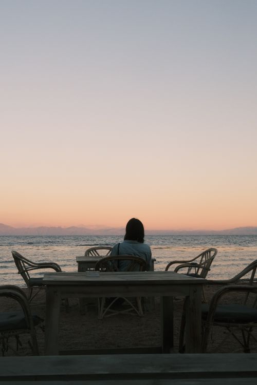 Free Tranquil scene of a woman gazing at the ocean at sunset. Stock Photo