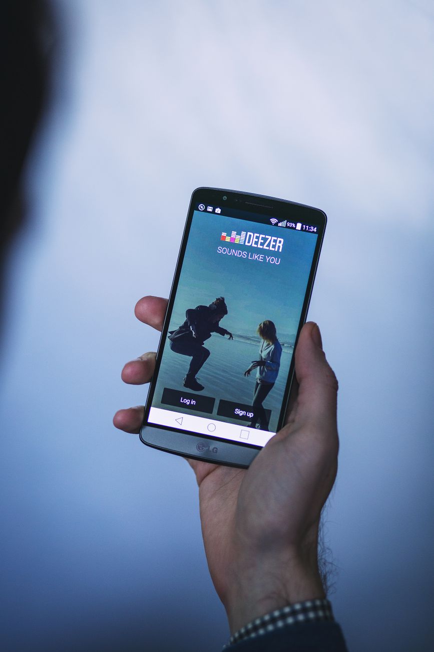 Person holding a smartphone displaying a music app